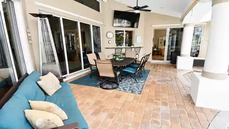 Covered patio with teal cushioned sofa, dining table for six and tall patio heater