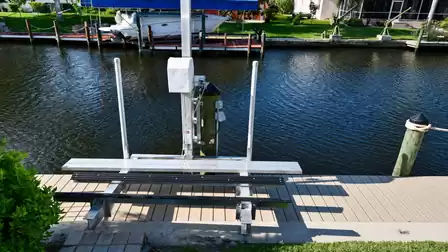 Jet ski lift on composite dock over canal water with covered boat opposite on pilings