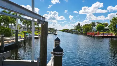 Canal beside metal boat lift frame, rope posts and bright red waterfront deck