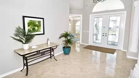 Entry hall with double glass front doors, marble tile floor and console table