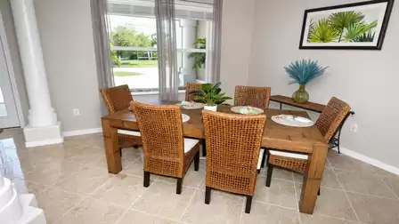 Dining area with wooden table, six wicker chairs, sideboard and palm artwork