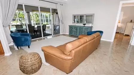 Living room with leather sofa, two blue armchairs, wicker stool and sliding doors