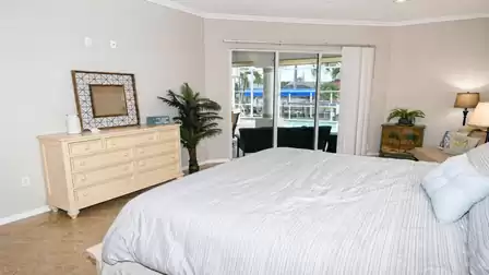 Bedroom with king-size bed, dresser and sliding doors opening to covered pool patio