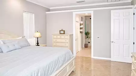 Bedroom with king-size bed, nightstand, dresser and open doorway leading to bathroom