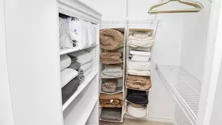 Walk-in closet with open shelves, hanging organizer compartments, linens, towels and hangers
