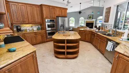 Kitchen with center island, granite countertops, double wall ovens and open living room beyond