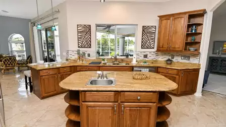 Kitchen island with small sink facing L-shaped counter, window and adjacent dining nook