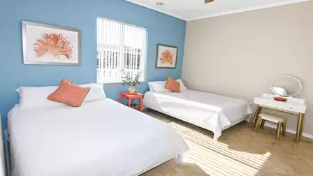 Bedroom with queen and twin beds, blue accent wall, coral artwork and vanity
