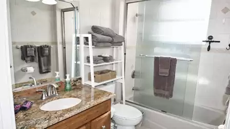 Bathroom with granite vanity, bathtub shower with ribbed glass doors and towel ladder