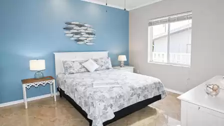 Bedroom with queen-size bed, blue feature wall, fish wall art and two lamps