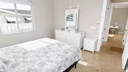 Bedroom with queen-size bed, white dresser with mirror, nightstand and hallway vanity table