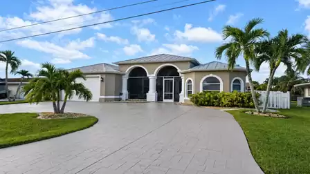 Front exterior of single-story home with arched screened entry, garage and circular driveway