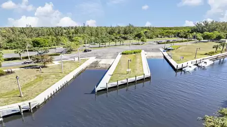 Twin concrete boat ramps into canal, flanked by docks, lampposts and multi-lane road