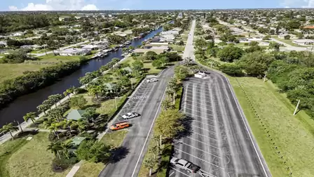 Waterfront park with palm-lined parking lot, green pavilions and canal-side homes
