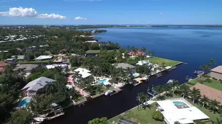 Aerial canal neighborhood with waterfront homes, docks, pools and wide open river