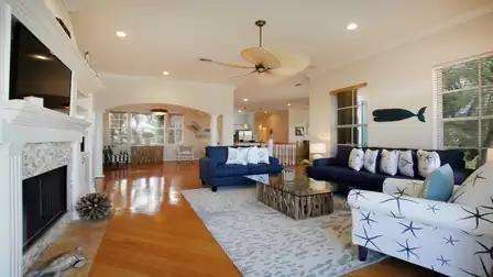 Open living room with blue sofas, fireplace, ceiling fan and patterned rug