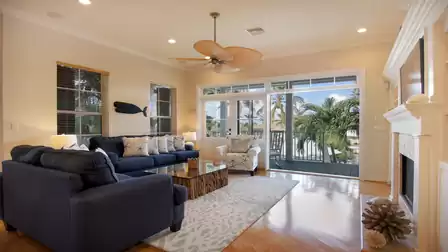 Living area with blue sectional sofa, patterned rug and balcony overlooking palm trees