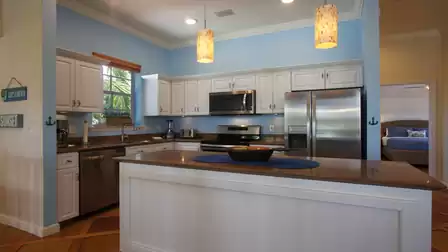 Kitchen with brown countertop island, stainless appliances and doorway to striped bedroom