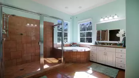 Bathroom with large glass shower, corner tub, double vanity and two windows