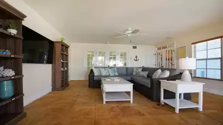 Living room with gray wicker sectional, white coffee table and wall of French doors