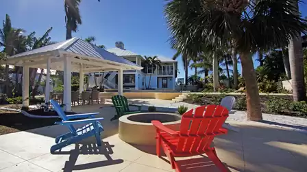 Patio with fire pit, colorful Adirondack chairs, white gazebo and palm trees