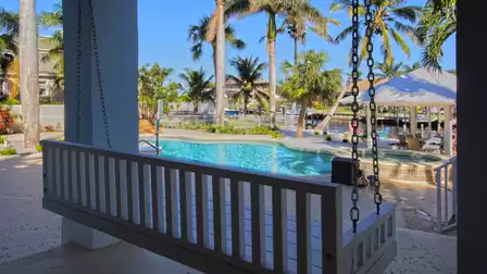 Covered patio with white porch swing overlooking freeform pool, spa and canal