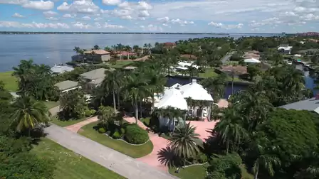 Aerial view of waterfront neighborhood with white house, canals and wide river