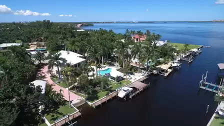 Aerial canalfront homes with white roofs, freeform pool, docks and wide river