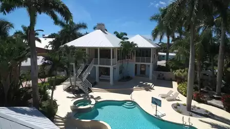 Two story house with white metal roof, curved pool, spa and exterior staircases