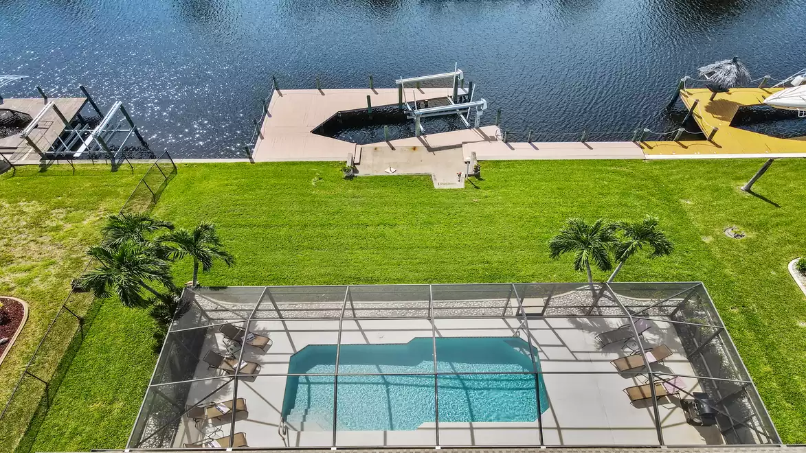 View from above of the pool terrace, the boat lift with dock and the canal