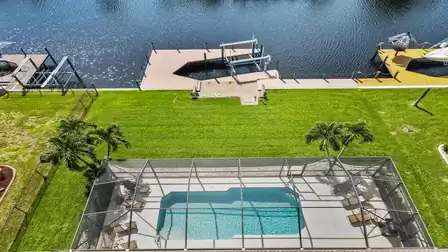 View from above of the pool terrace, the boat lift with dock and the canal