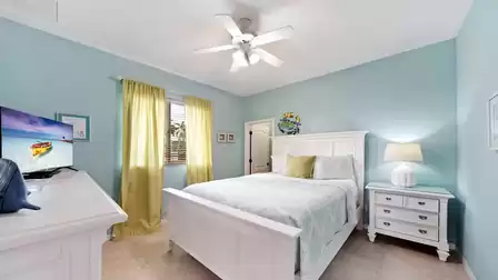 The third bedroom is modern, furnished with a queen bed and a TV