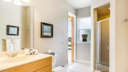 The guest bathroom has a walk-in shower and serves as a pool bath