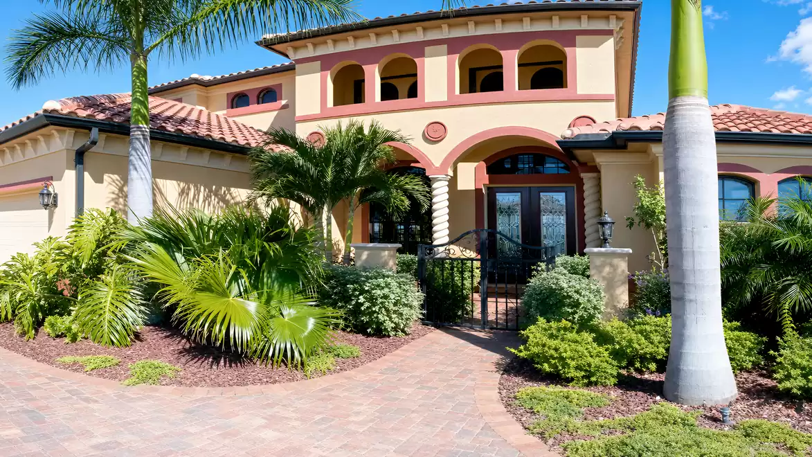 Mediterranean villa with palm trees, landscaped front yard, gated entrance, arches and paved driveway