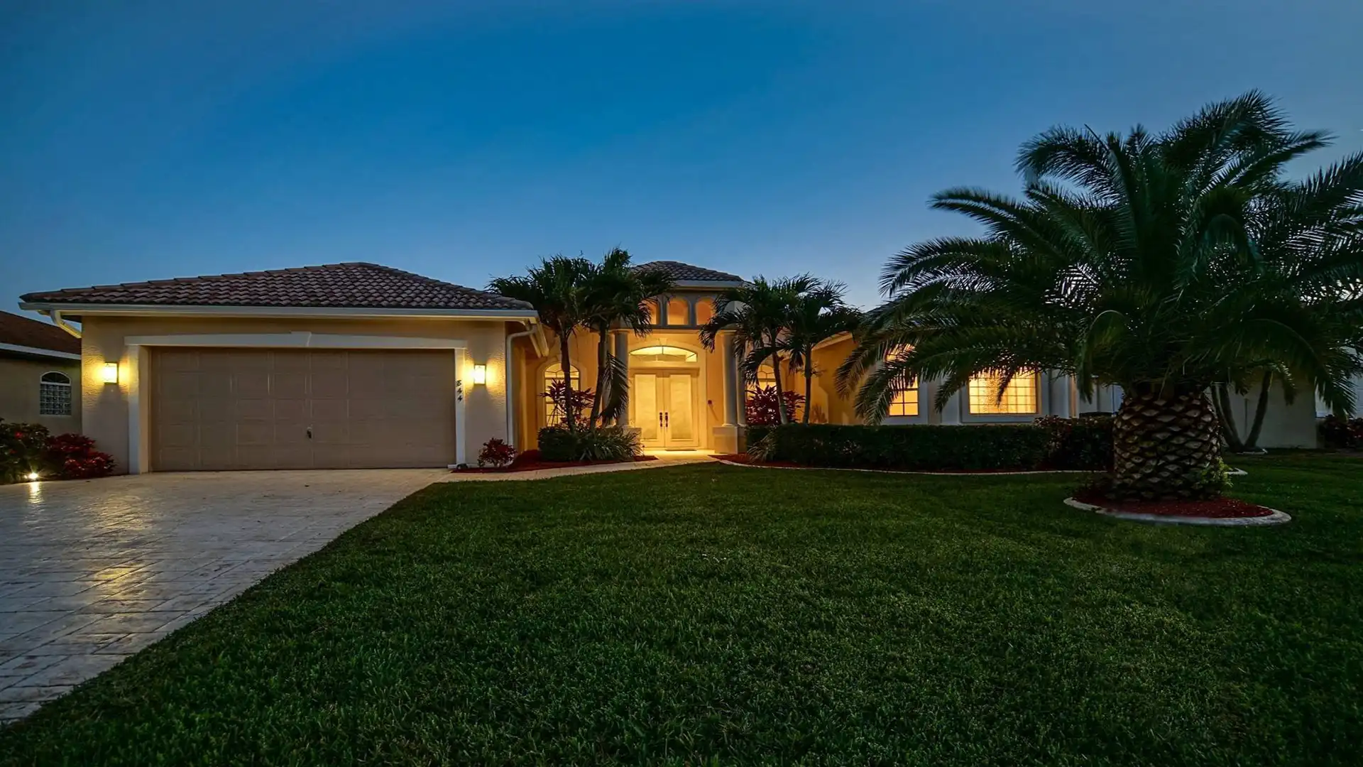 Evening view of Villa Camille with lights and palm trees.