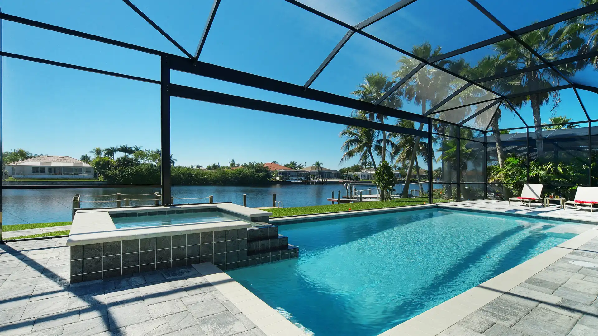 Large screened pool area with sun loungers right by the water.