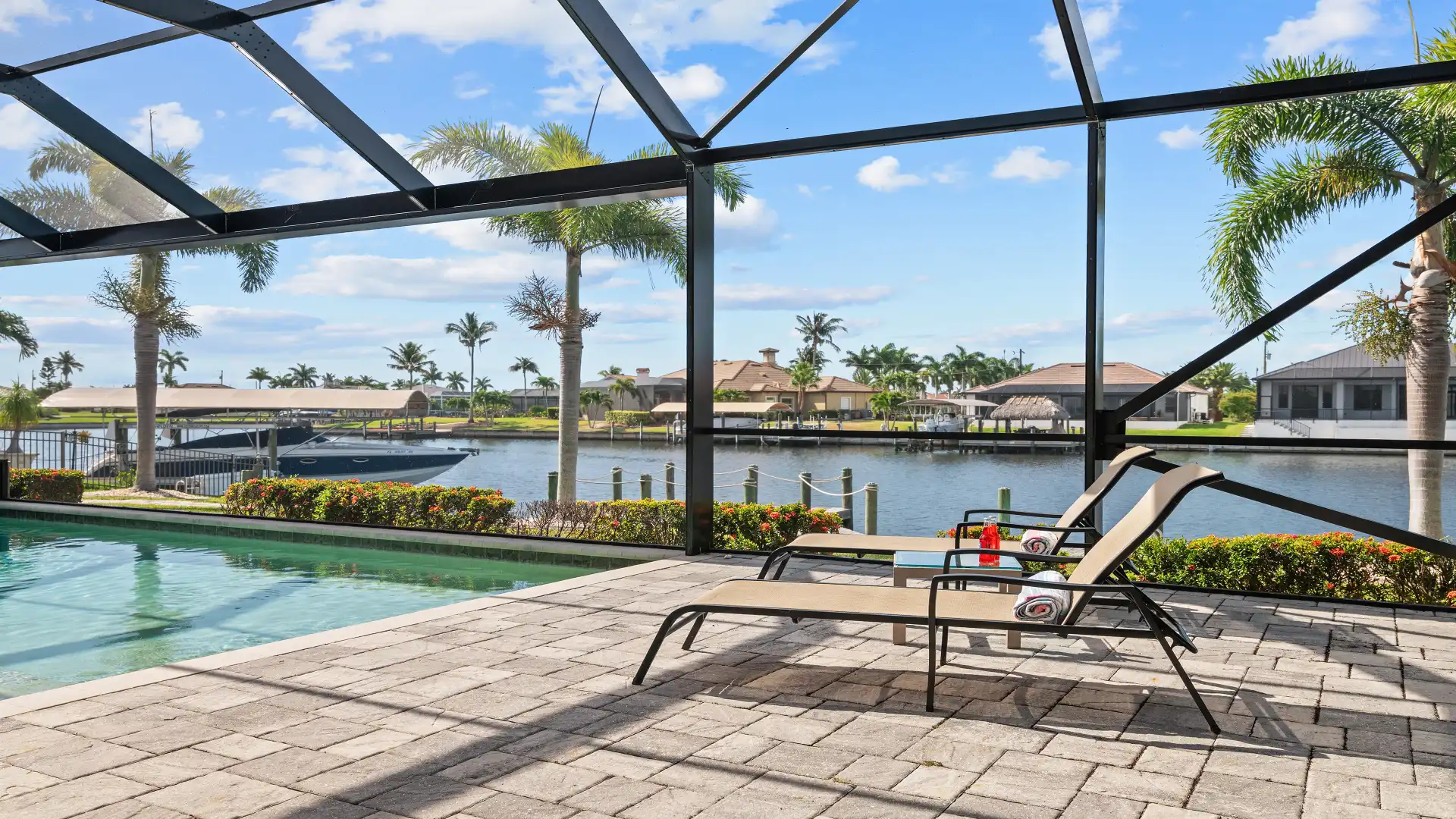 Sun loungers by the pool area of Villa Elvenar overlooking the canal with a luxury motorboat in the background.