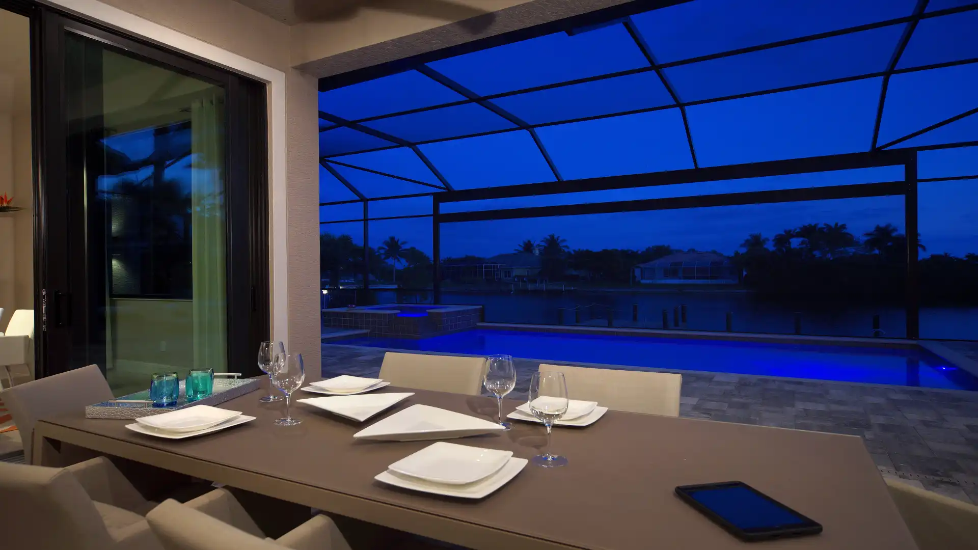 Atmospheric evening setting on the covered terrace with a view of the illuminated pool.