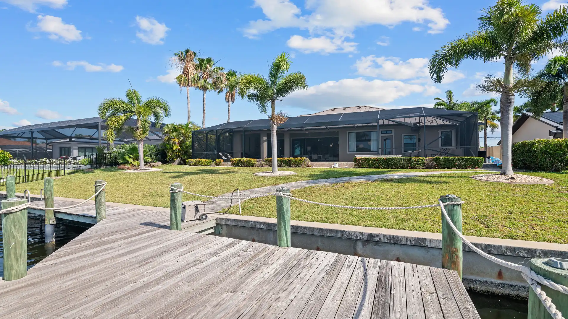 View from the boat dock of the vacation home with a spacious garden and palm trees.