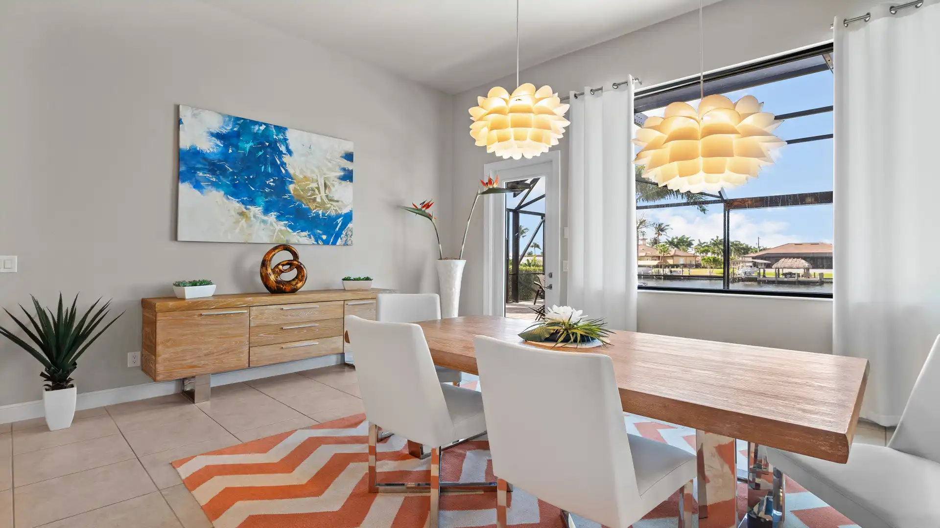  Bright dining area with a large wooden table, white chairs, and stylish pendant lights, overlooking the canal.