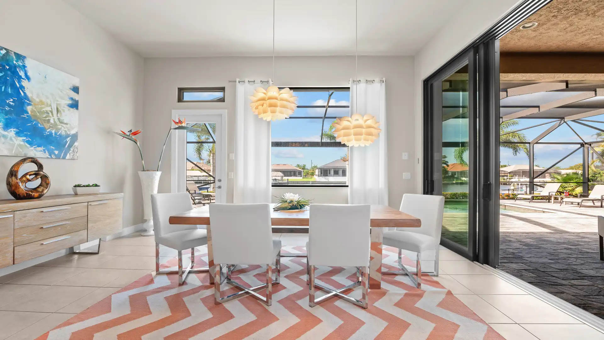 Dining area with designer pendant lights, open to the terrace with a stunning view of the waterway.