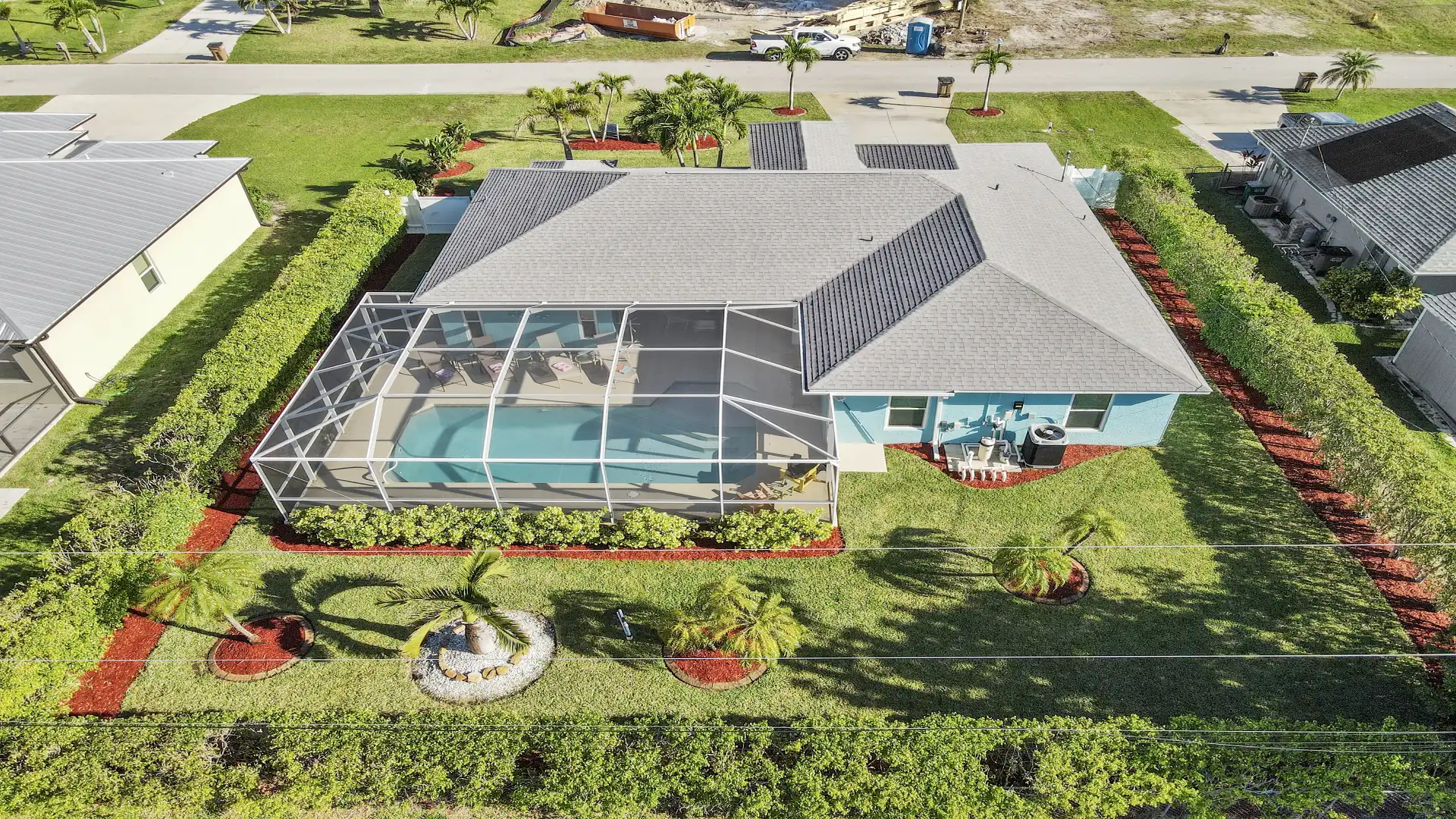 Spacious, well-kept garden with palm trees and screened pool area
