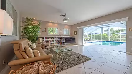 Cozy living area with sofas, bookshelf and direct access to the pool terrace filled with natural light.