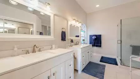 Large, almost completely white bathroom with bathtub, shower, double sink & toilet
