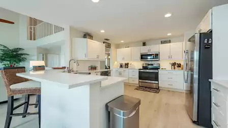 Spacious modern kitchen with island, white cabinets, stainless steel appliances and open connection to the living area.