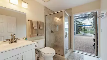 Modern bathroom with glass shower, bright vanity and direct access to the pool terrace with lake view.