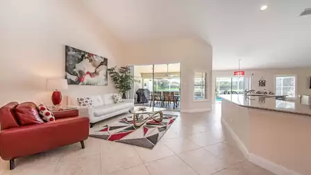 Open living area with sofas, modern kitchen, plenty of natural light and seamless access to the pool terrace.
