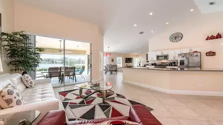 Spacious open living and kitchen area with sofas, kitchen island, plenty of natural light and access to the pool terrace.